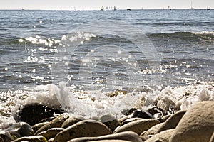 View of the Mediterranean Sea, large stones on the shore. In the background are ships and sailboats. sunny day. View of
