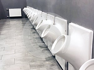 View of men`s round shaped pipe urinals in a public toilet