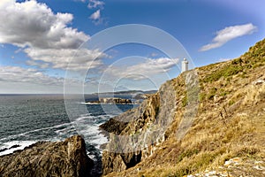 View of Mera lighthouse on a cliff on the atlantic coast of Spain in La CoruÃÂ±a. Sky with clouds and sun facing