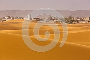 View of Merzouga town in background in Desert Sahara with beautiful lines and colors at sunrise. Merzouga, Morocco photo