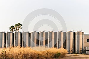 View of metallic industrial storage tanks in a row under the blue sky