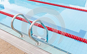 The view of metallic ladder of swimming pool with marked lanes.