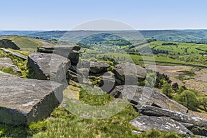 A view of millstone boulders balanced on the cliff top at the Stanage Edge escarpment in the Peak District, UK