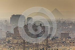 View of misty Cairo skyline with pyramids in the background, Egy