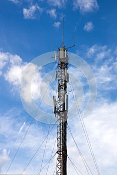 View of a mobile phone antenna from the ground with clouds and glades in the blue sky photo