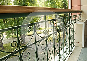 View from a modern balcony through a metal openwork wrought iron fence with railings to the Park on a Sunny summer day