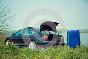 View of modern black car and suitcase on the river`s side