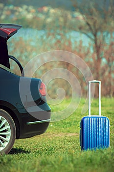 View of modern black car and suitcase on the river`s side