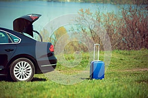 View of modern black car and suitcase on the river`s side