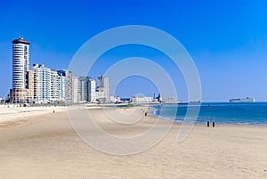 View of a modern coastal city or town and its beach. Big cargo ships in the sea. Summer concept. Vacation.