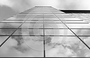 View of a modern glass skyscraper. A reflection of the cloudy sky in a glass skyscraper. Black and white photo