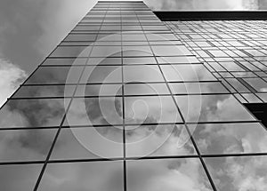 View of a modern glass skyscraper. A reflection of the cloudy sky in a glass skyscraper. Black and white photo