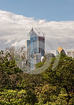 View of Modern high buildings among green trees space in nature against blue sky with clouds at afternoon