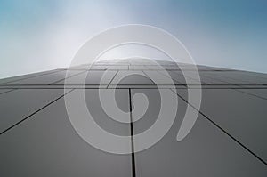 View through modern high rising skyscraper upwards to blue sky with white clouds - abstract architecture detail background