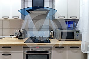 View of a modern kitchen with blue hood, kitchen appliances and dining table