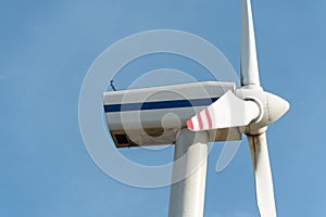 view of a modern windmill against a blue sky. The white blades of the wind turbine close up. Renewable energy source. Production