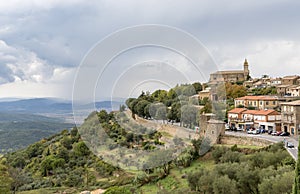 View of the Montalcino Cathedral and houses on the hill, fortress wall around the town and surroundings of Montalcino, Tuscany