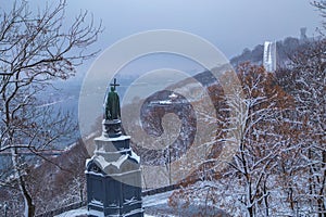 View of the monument to Vladimir the Holy through snow-covered trees in Vladimirsky park and view of the Dnieper river in the city