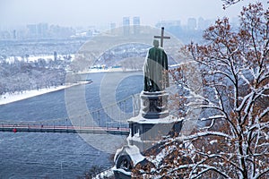 View of the monument to Vladimir the Holy through snow-covered trees in Vladimirsky park and view of the Dnieper river in the city