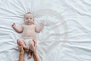 View of mother touching legs of baby daughter in diaper