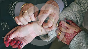 View of a mother tying a gold bracelet to her daughter during wedding day