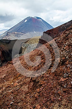 View of Mount Ngauruhoe - Mount Doom from Tongariro Alpine Crossing hike with clouds above and red crater in foreground