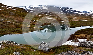 View of a mountain lake that partially reflects a mountain. Camp