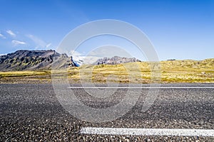 a view of mountains in the distance from the side of a highway