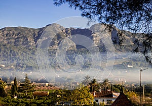 View of mountains and spanish village in the valley in morning mist