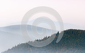 View of a mountains valley in a early morning with fog between hills. Mountains ranges layers.