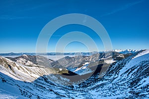 View of mountains west Tatra mountains and valley with fog and blue sky from ridge in Low Tatras, Slovakia