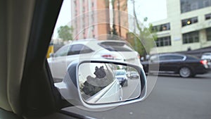 View from moving automobile, reflection in rearview mirror. Traffic jam in city