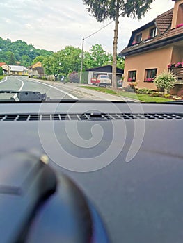 View from a moving car passing a village street and passing a vintage car