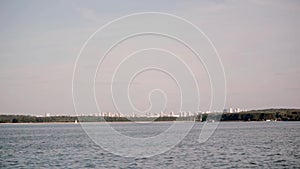 View from the moving ship to the city landscape. Sunny bright day in the open water, lake with blue water scenery.