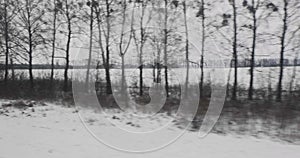 View from the moving train window on winter dull gray landscape with snow and trees