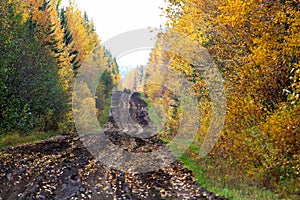 A view of a muddy autumn road with hunters on quads in the background