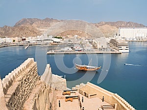 View from Mutrah Fort on the entrance to the Mutrah port in Muscat with a traditional Omani boat Dhow and in the background the