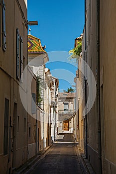 View of a narrow alley with sunny blue sky, in the city center of Nimes.