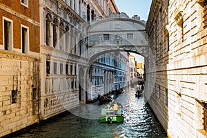 View of narrow canal with motor boat and gondolas in Venice