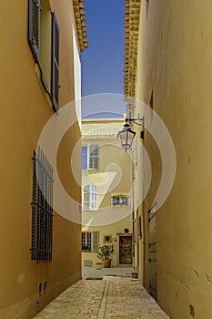 View of a narrow picturesque French street with yellow-colored buildings and flower boxes