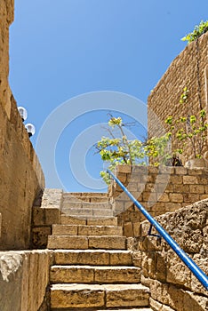 View of a narrow stone street through a staircase in the old city of Jaffa, with the old houses still