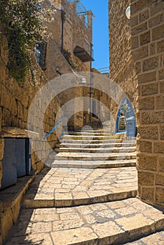 View of a narrow stone street through a staircase in the old city of Jaffa, with the old houses still