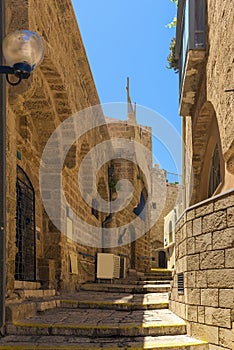 View of a narrow stone street through a staircase in the old city of Jaffa, with the old houses still