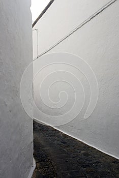 A view of a narrow street with arch and wooden windows and doors with white wall stone architecture of the island Patmos, Greece