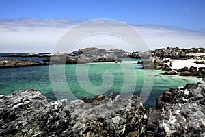 View on natural turquoise pool surrounded by jagged rocks with altostratus clouds in the horizon