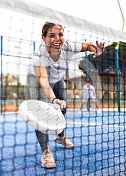 View through net of young female paddle tennis player