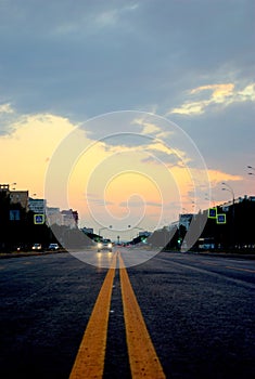 View of a new asphalt road with yellow markings closeup and sunset sky in the background.