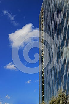 View of new highrise office building against blue sky with cloud reflections