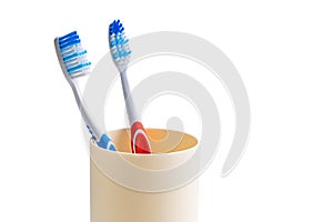 View of new toothbrush red and blue handle in plastic cup isolated on white background