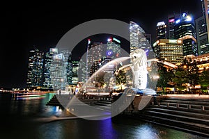 View of night central Singapore cityscape. Merlion lion fountain sculpture with financial tower building and night sky background